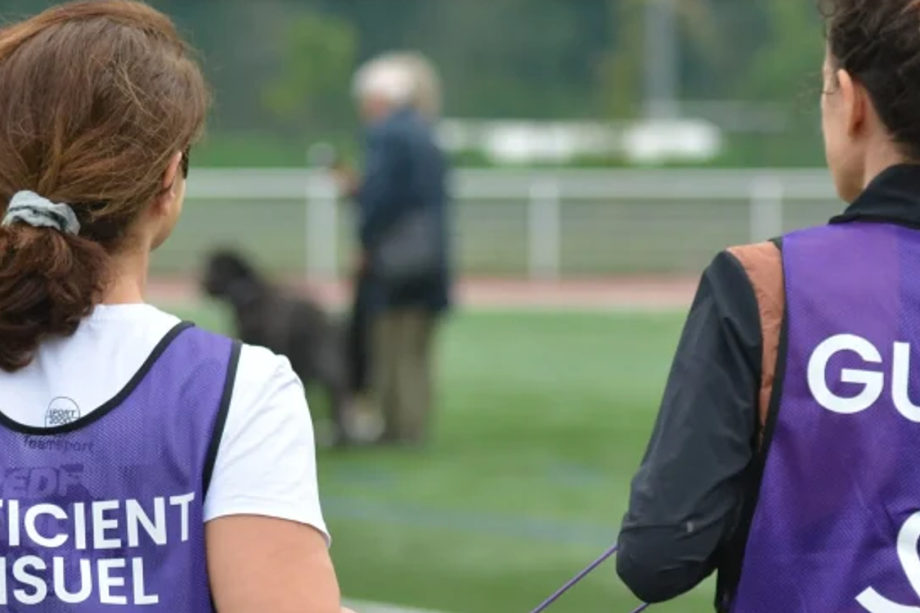 Two people seen from behind wearing sports bibs on a playing field