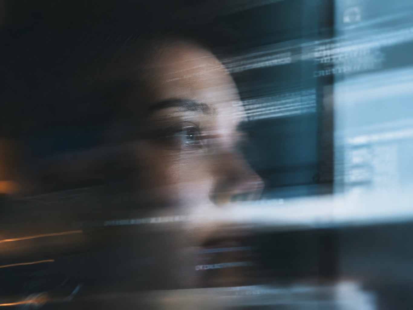 Profile of a woman looking at a screen, her face overlaid with lines of code and terminal windows